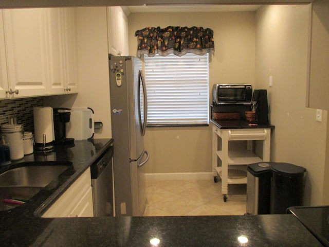 kitchen featuring light tile patterned floors, sink, appliances with stainless steel finishes, white cabinets, and decorative backsplash