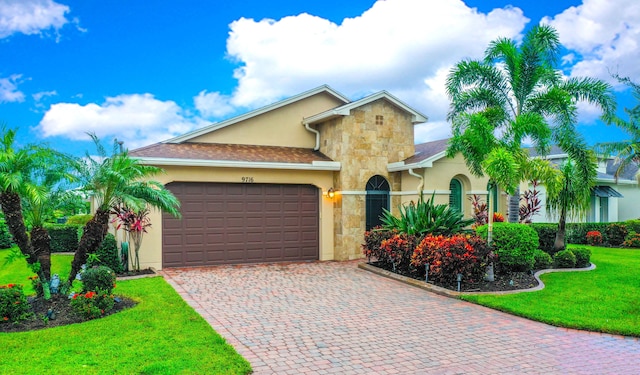 9716 SW Chestwood Ave, Port Saint Lucie, FL 34987 - view of front of home featuring stucco siding, decorative driveway, stone siding, a front lawn, and a garage
