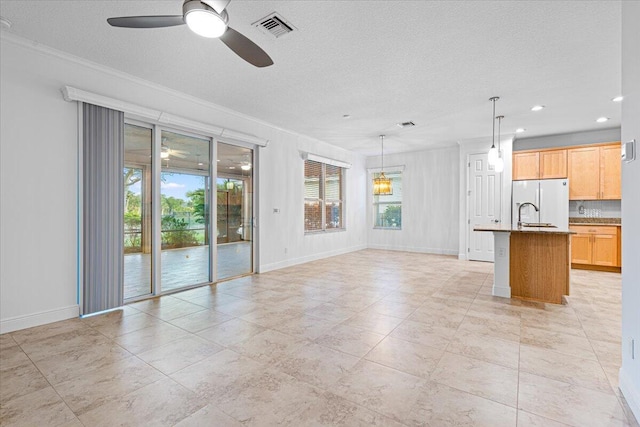 unfurnished living room with ceiling fan, sink, a textured ceiling, and ornamental molding