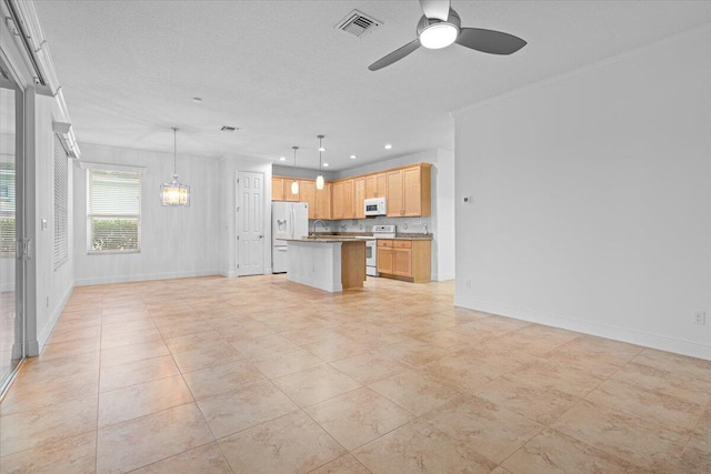 kitchen featuring white appliances, ceiling fan, crown molding, decorative light fixtures, and a center island with sink