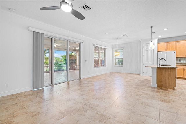 unfurnished living room featuring ceiling fan, crown molding, and a textured ceiling