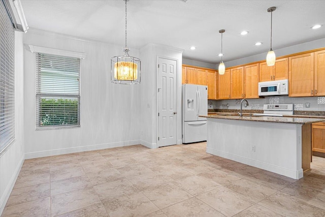 9716 SW Chestwood Ave, Port Saint Lucie, FL 34987 - kitchen with dark stone counters, an inviting chandelier, white appliances, a center island with sink, and baseboards