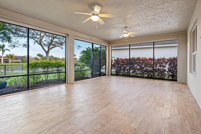 unfurnished sunroom featuring ceiling fan and a water view