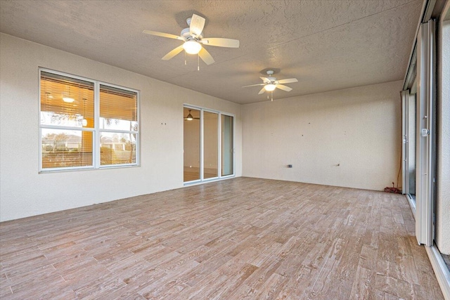 interior space featuring ceiling fan, light hardwood / wood-style floors, and a textured ceiling