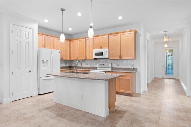 kitchen featuring light brown cabinetry, white appliances, sink, pendant lighting, and an island with sink