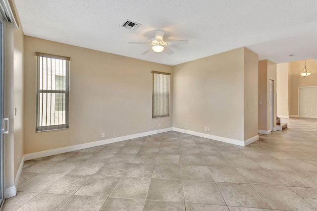 unfurnished room with ceiling fan and a textured ceiling