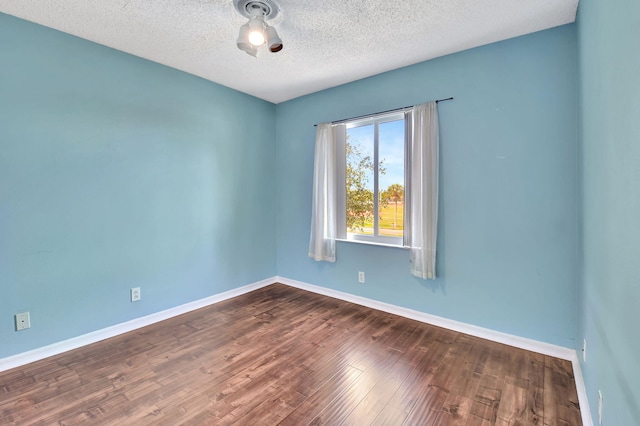 empty room featuring a textured ceiling and dark wood-type flooring