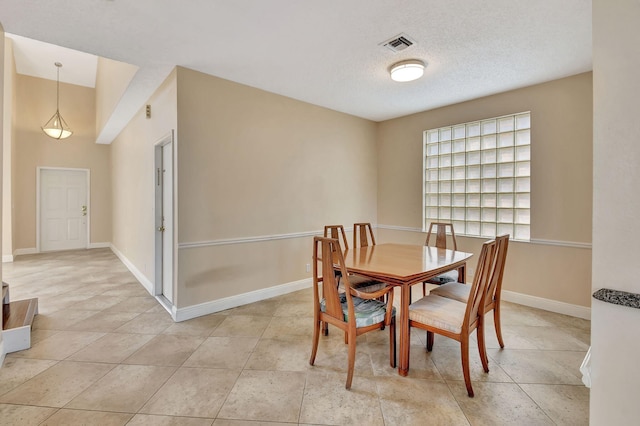 dining space featuring light tile patterned floors and a textured ceiling