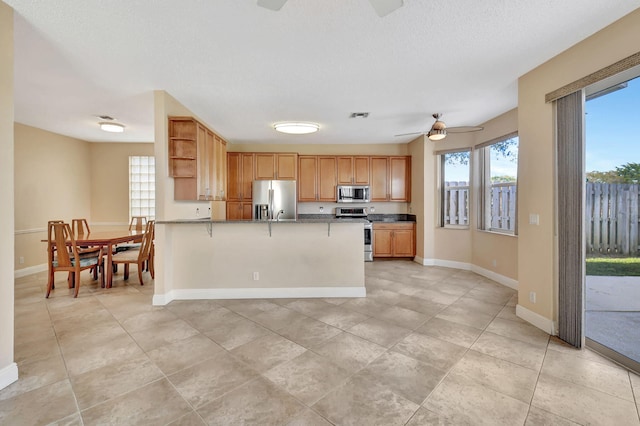 kitchen with a kitchen breakfast bar, stainless steel appliances, plenty of natural light, and ceiling fan