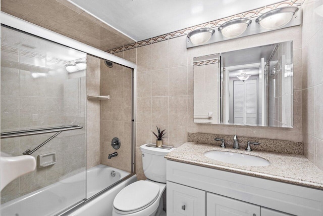 full bathroom featuring tile walls, vanity, enclosed tub / shower combo, and toilet