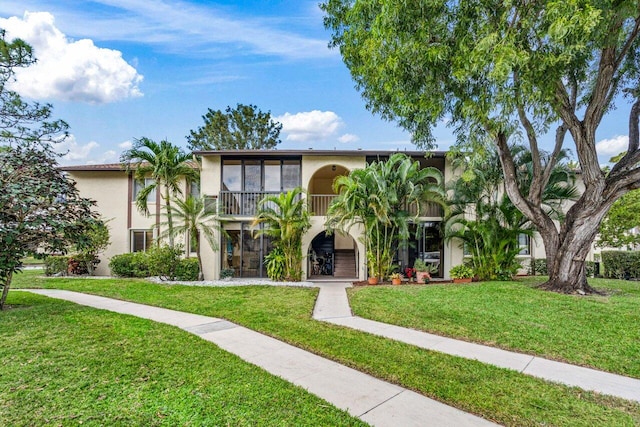 view of front of property featuring a balcony and a front yard