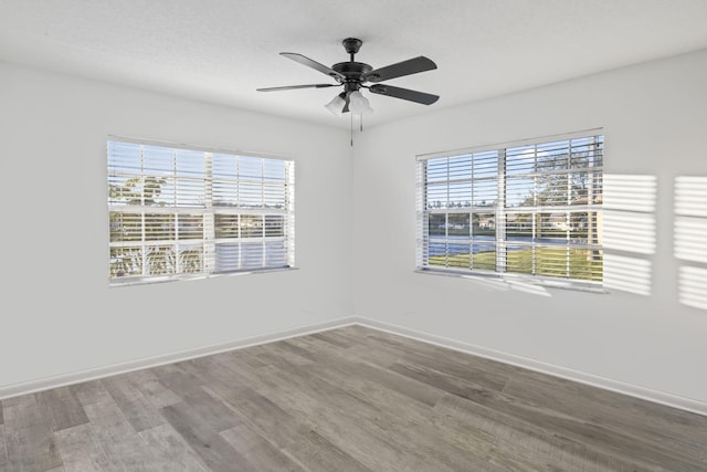 spare room with ceiling fan, hardwood / wood-style floors, and a wealth of natural light