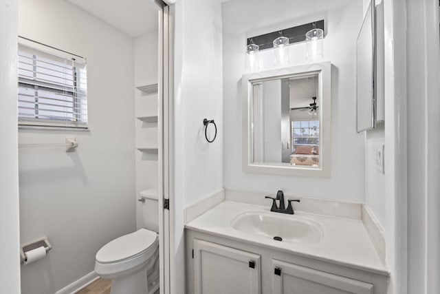 bathroom featuring toilet, vanity, and ceiling fan