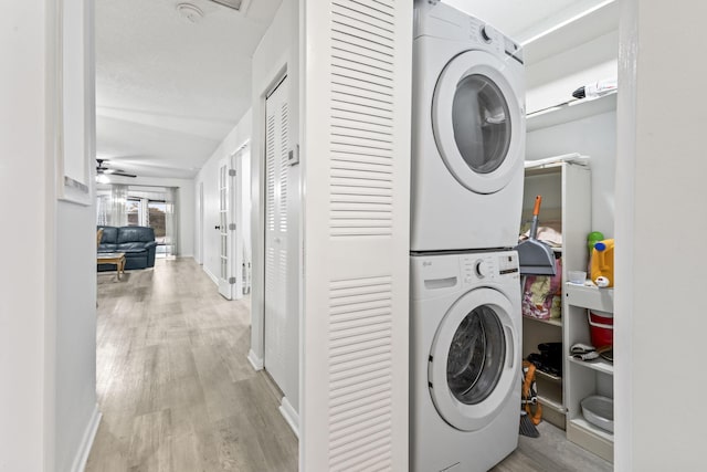 laundry room featuring ceiling fan, light wood-type flooring, and stacked washer / dryer