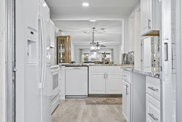 kitchen with white appliances, hanging light fixtures, light wood-type flooring, and white cabinets