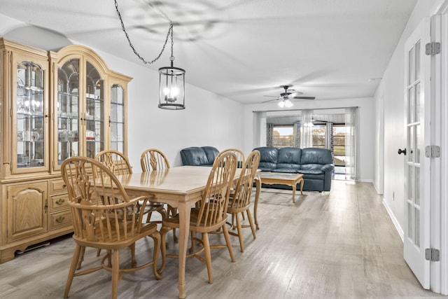 dining area with ceiling fan with notable chandelier and light wood-type flooring