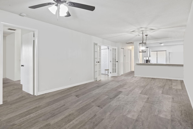 unfurnished living room with ceiling fan with notable chandelier and hardwood / wood-style floors