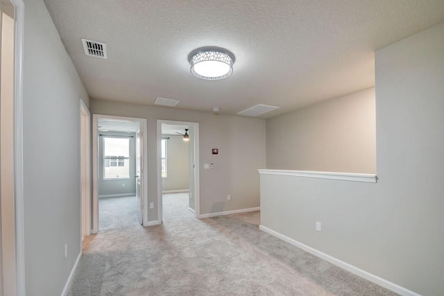 unfurnished room with ceiling fan, light colored carpet, and a textured ceiling