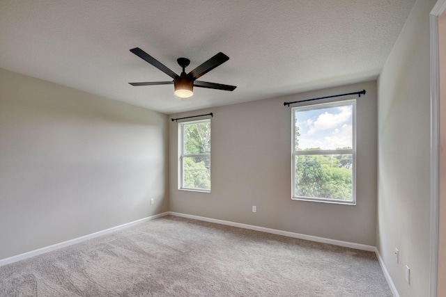 carpeted empty room with ceiling fan, plenty of natural light, and a textured ceiling