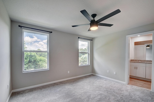 unfurnished bedroom with connected bathroom, ceiling fan, sink, light colored carpet, and a textured ceiling