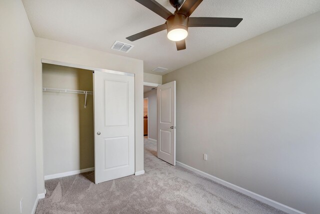 unfurnished bedroom featuring ceiling fan, a closet, and light colored carpet