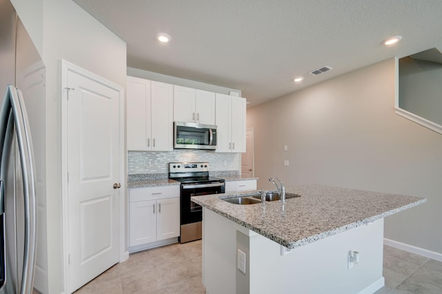 kitchen with tasteful backsplash, stainless steel appliances, a kitchen island with sink, sink, and white cabinets