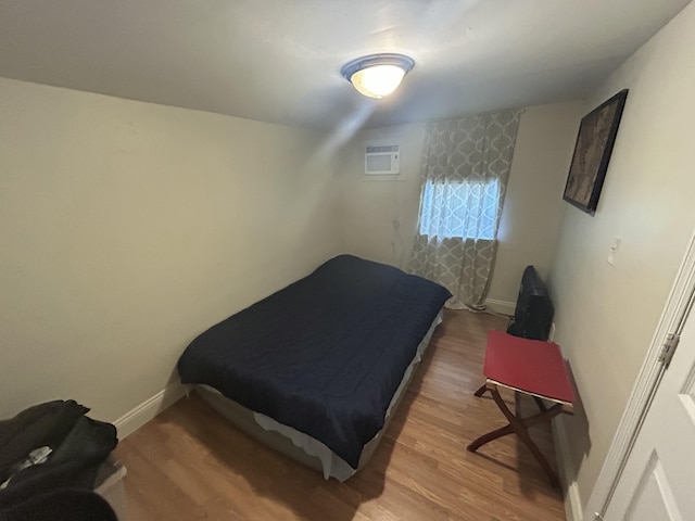 bedroom with wood-type flooring and a wall unit AC