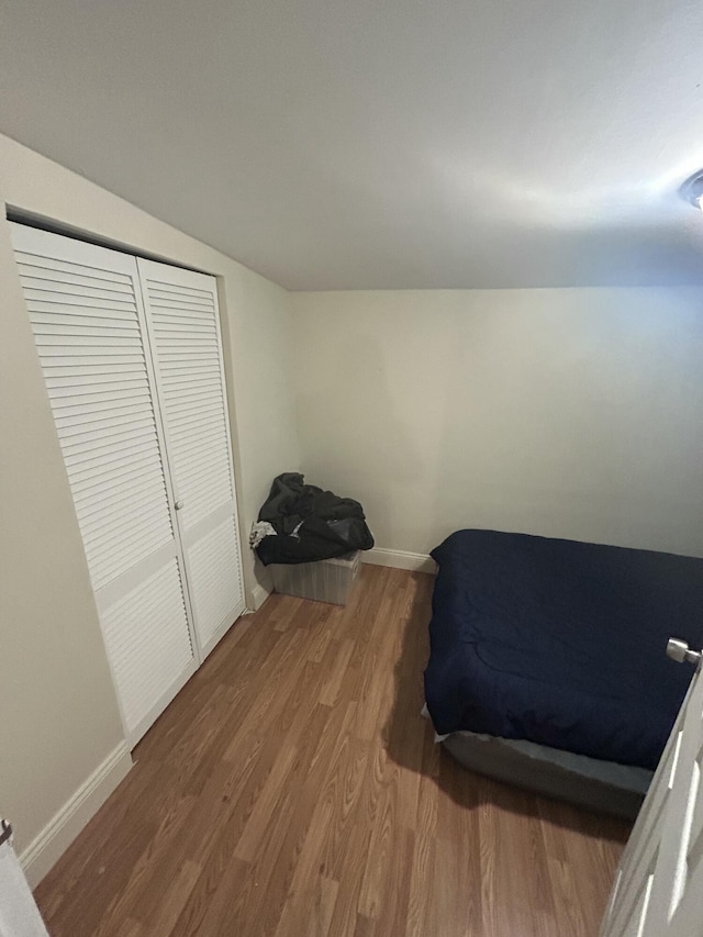 bedroom featuring lofted ceiling, a closet, and hardwood / wood-style flooring