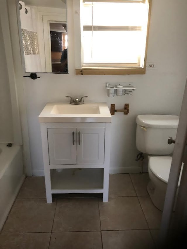 bathroom with toilet, tile patterned floors, a washtub, and vanity