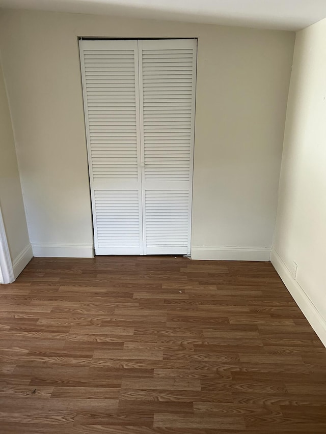 unfurnished bedroom featuring a closet and dark hardwood / wood-style flooring