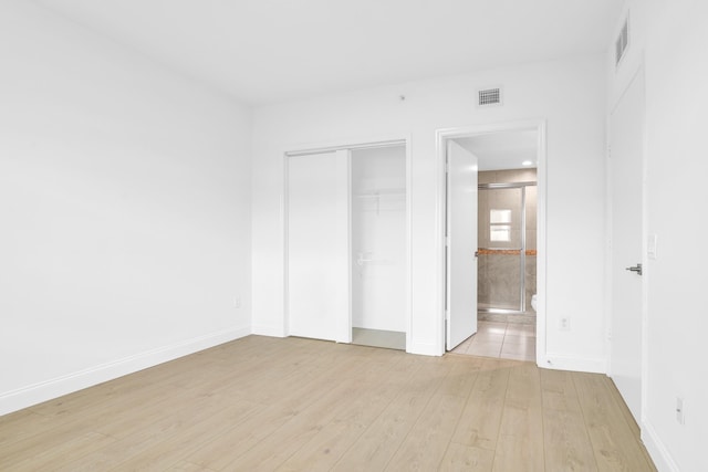 unfurnished bedroom featuring light hardwood / wood-style floors and connected bathroom