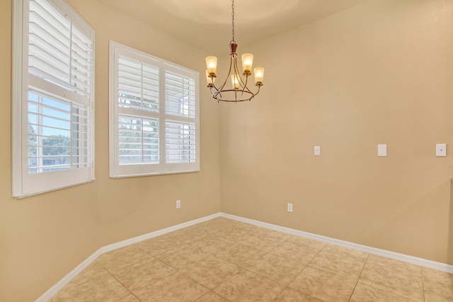 spare room with tile patterned floors and a chandelier