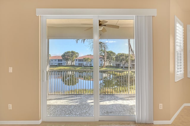 doorway to outside featuring a water view, ceiling fan, and tile patterned floors