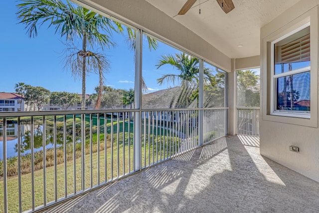 unfurnished sunroom with ceiling fan and a water view