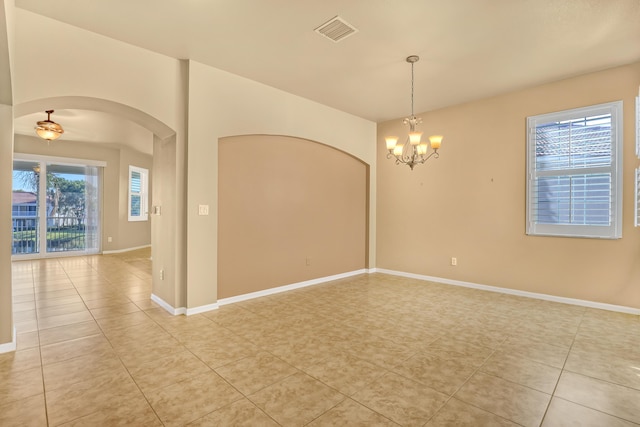 empty room with light tile patterned flooring and a chandelier