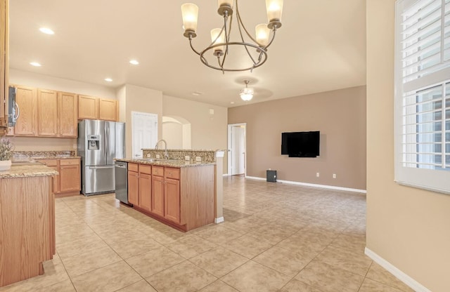 kitchen featuring decorative light fixtures, stainless steel appliances, sink, a notable chandelier, and light stone counters