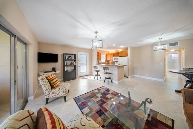 living room with light tile patterned flooring, a textured ceiling, and a chandelier