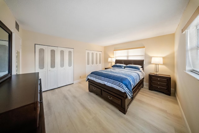 bedroom with light hardwood / wood-style flooring and two closets