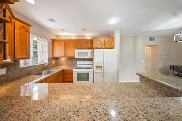 kitchen with decorative backsplash, sink, light stone counters, and white appliances