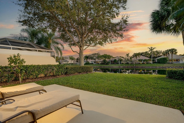 patio terrace at dusk with a lawn and a water view