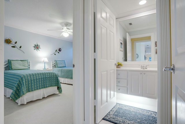 carpeted bedroom with ensuite bath, ceiling fan, crown molding, and sink