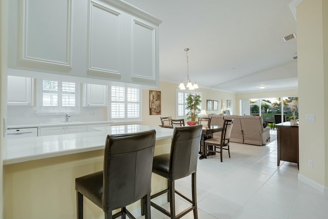 kitchen with a kitchen bar, sink, light tile patterned floors, a notable chandelier, and white cabinetry