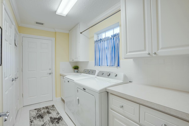 laundry room with cabinets, ornamental molding, a textured ceiling, light tile patterned floors, and separate washer and dryer