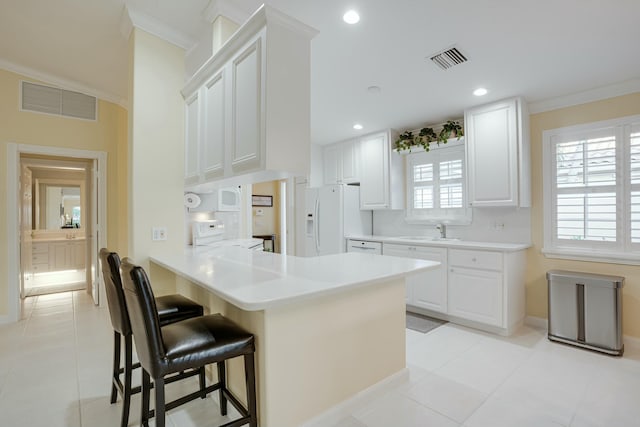 kitchen with kitchen peninsula, white cabinets, white refrigerator with ice dispenser, and range