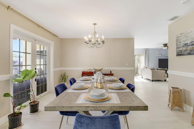 dining space featuring french doors and ceiling fan with notable chandelier