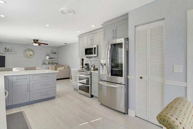 kitchen featuring gray cabinetry, ceiling fan, stainless steel appliances, and tasteful backsplash