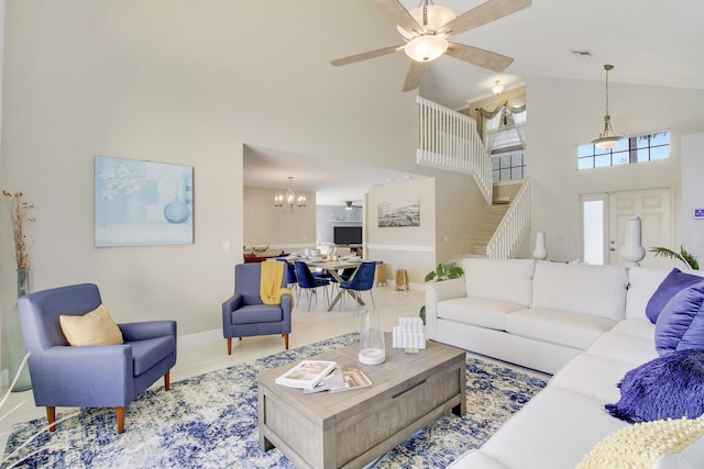 living room with ceiling fan with notable chandelier and a towering ceiling