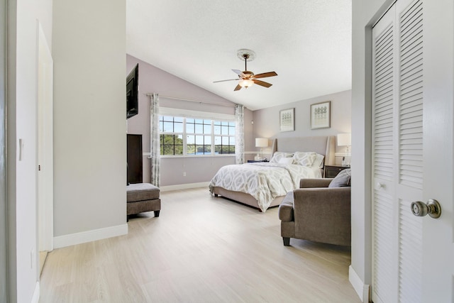 bedroom with ceiling fan, light hardwood / wood-style floors, and vaulted ceiling