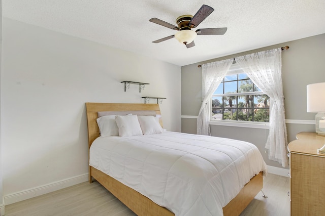 bedroom featuring ceiling fan, light wood-type flooring, and a textured ceiling