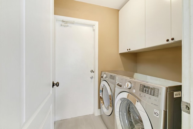 clothes washing area featuring cabinets and washing machine and clothes dryer